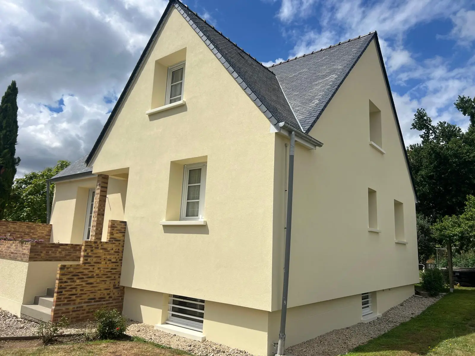 Maison au crépi neuf, couleur sable, sous un ciel bleu