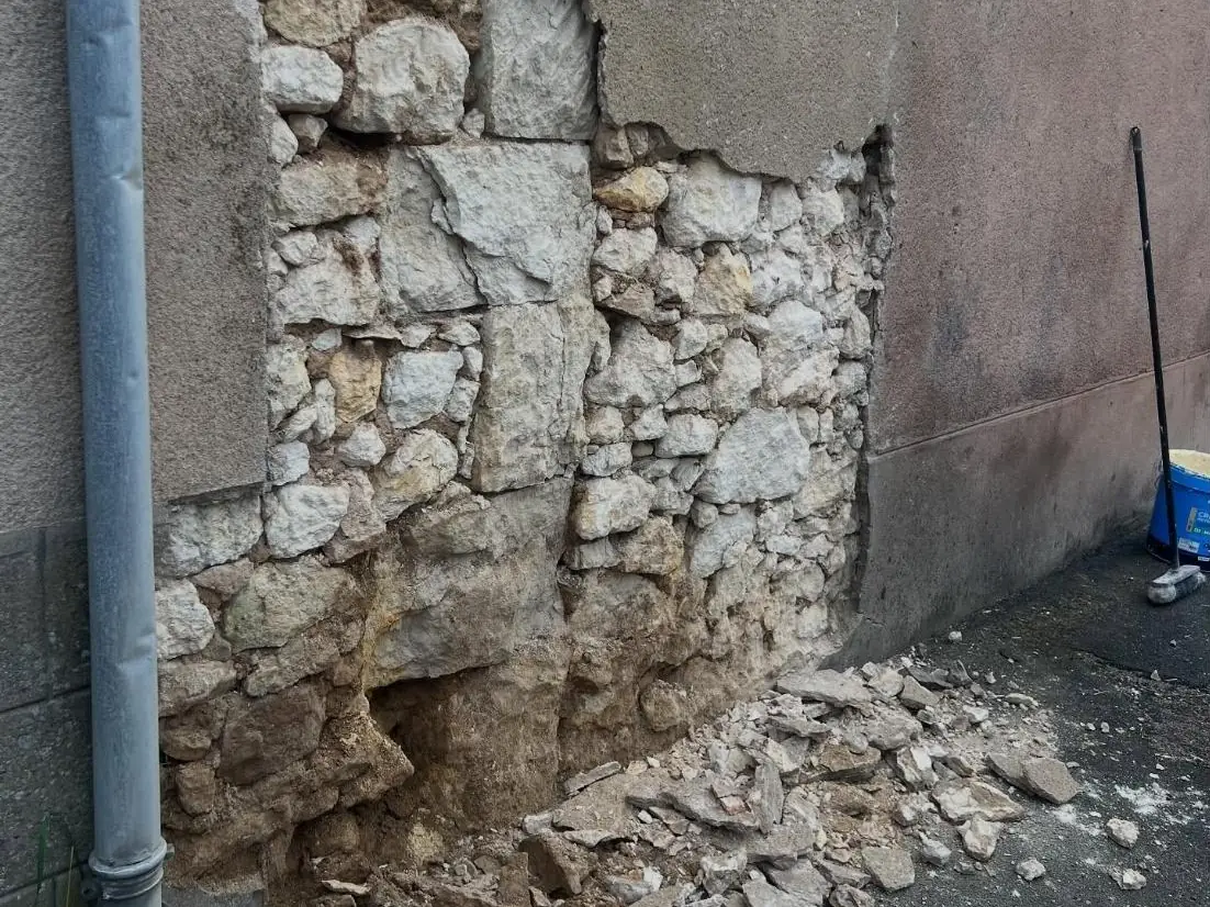 Avant : l'enduit et les pierres du mur tombés au pied de la gouttière